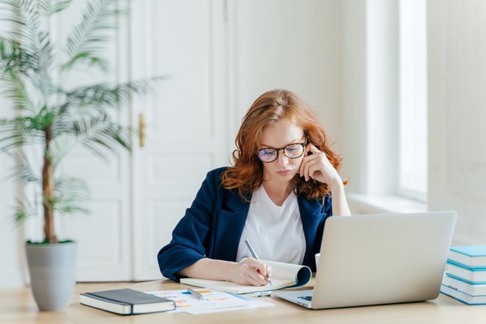 A female lawyer sitting behind a desk works on her laptop