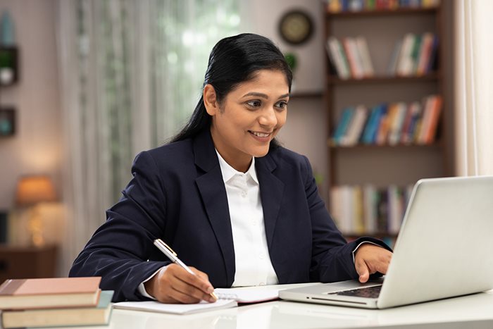 A female attorney takes notes as she looks up online reputation management for attorneys on her computer.