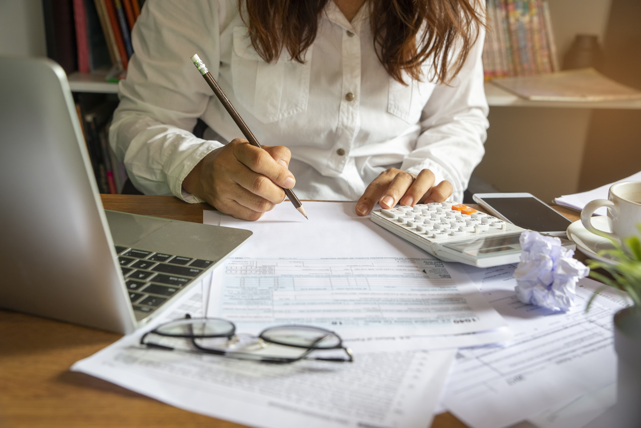 A legal professional peruses paperwork and uses a calculator as she works on her law firm business strategy.