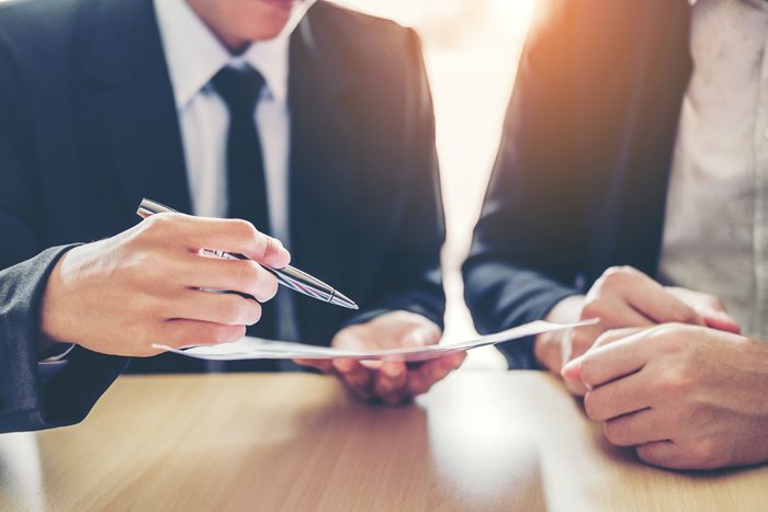 A close-up of two lawyers pursuing a document and discussing how to write better engagement letters.